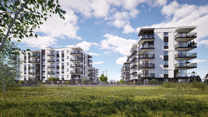 Nowoczesne bloki mieszkalne z balkonami, trawnik i drzewa na pierwszym planie pod błękitnym niebem.