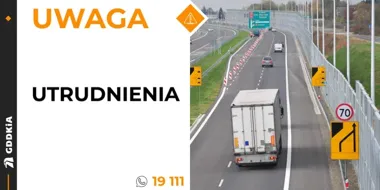 Fragment autostrady z wąskim pasem ruchu, oznakowanym ograniczeniem prędkości do 70 km/h i znakami kierunkowymi, na którym poruszają się pojazdy.